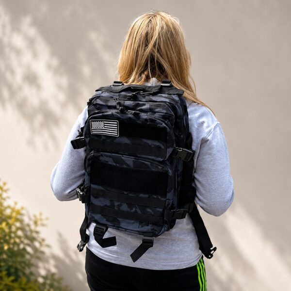 Black camo tactical backpack with adjustable straps and American flag patch worn by female model